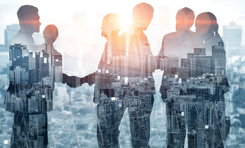 Silhouettes of business colleagues shaking hands over a cityscape, symbolizing collaboration.